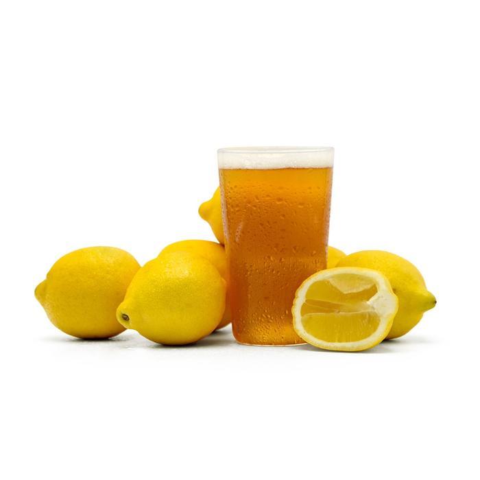 Summer Squeeze Lemon Shandy homebrew in a glass surrounded by whole and cut lemons
